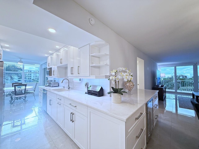 kitchen with appliances with stainless steel finishes, a wealth of natural light, white cabinetry, and light stone countertops