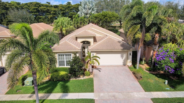 mediterranean / spanish house featuring a garage, stucco siding, a tile roof, decorative driveway, and a front yard