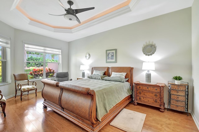 bedroom featuring crown molding, ceiling fan, a raised ceiling, and light wood-type flooring