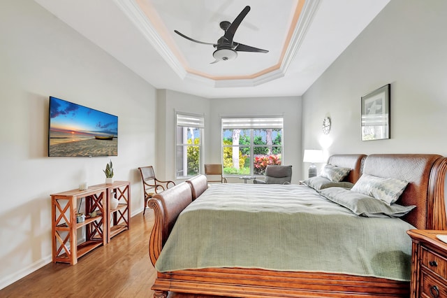 bedroom with hardwood / wood-style floors, ornamental molding, a raised ceiling, and ceiling fan