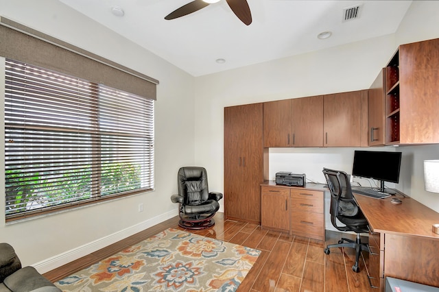 office space featuring built in desk, light hardwood / wood-style flooring, and ceiling fan