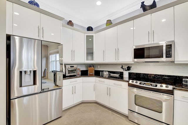 kitchen with crown molding, dark stone countertops, appliances with stainless steel finishes, decorative backsplash, and white cabinets