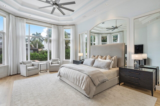 bedroom featuring ceiling fan, crown molding, light hardwood / wood-style flooring, and a raised ceiling