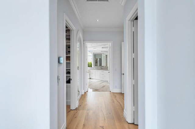 corridor with light hardwood / wood-style flooring and ornamental molding