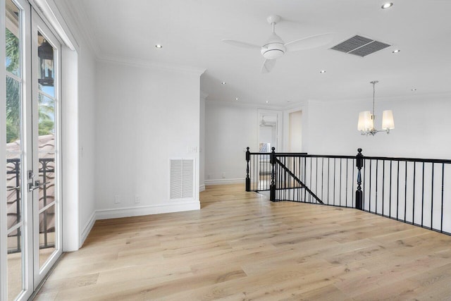 unfurnished room with light wood-type flooring, ornamental molding, and ceiling fan with notable chandelier