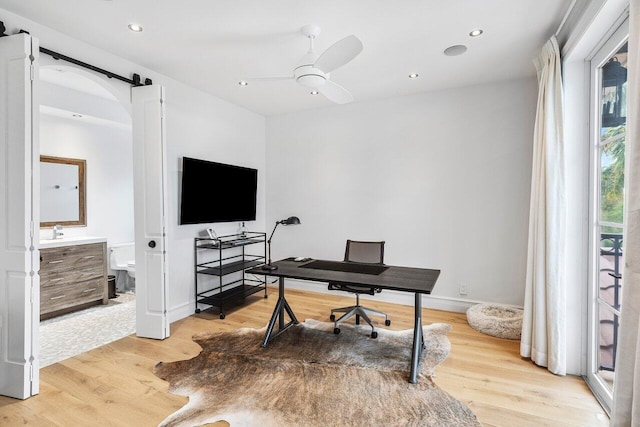 home office with light wood-type flooring, ceiling fan, and sink