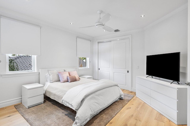 bedroom featuring hardwood / wood-style floors, multiple windows, a closet, ceiling fan, and crown molding