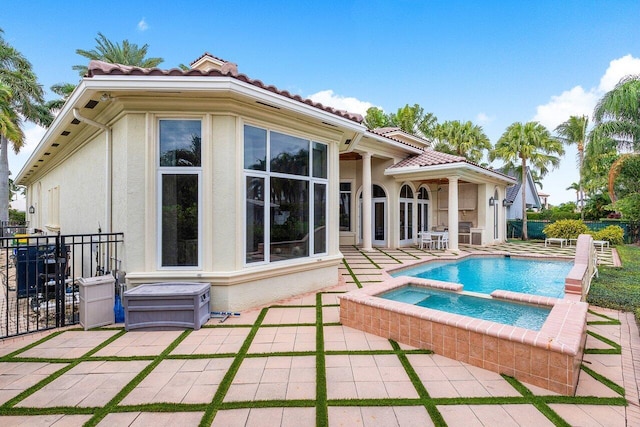 rear view of property with a patio area and an in ground hot tub