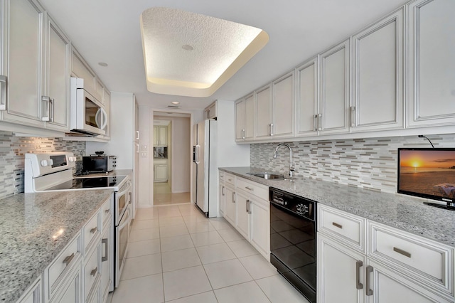 kitchen featuring sink, light stone counters, white cabinets, and white appliances