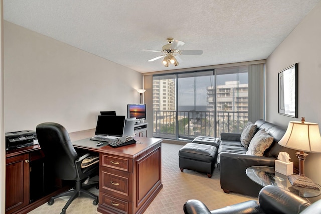 office area with ceiling fan, light carpet, a textured ceiling, and a wall of windows