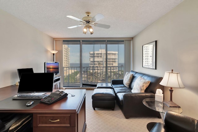 carpeted office with ceiling fan, a textured ceiling, and a wall of windows