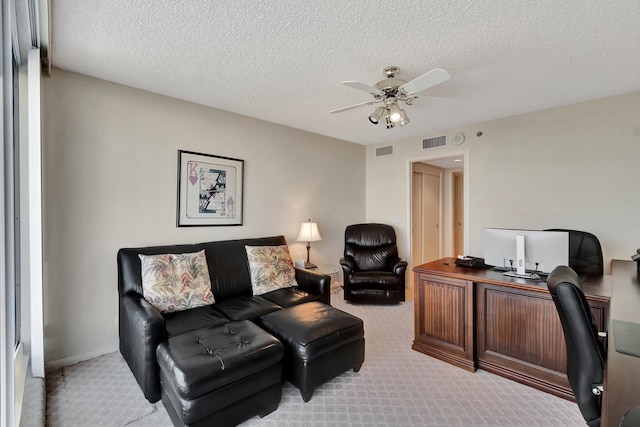 home office featuring light carpet, a textured ceiling, and ceiling fan