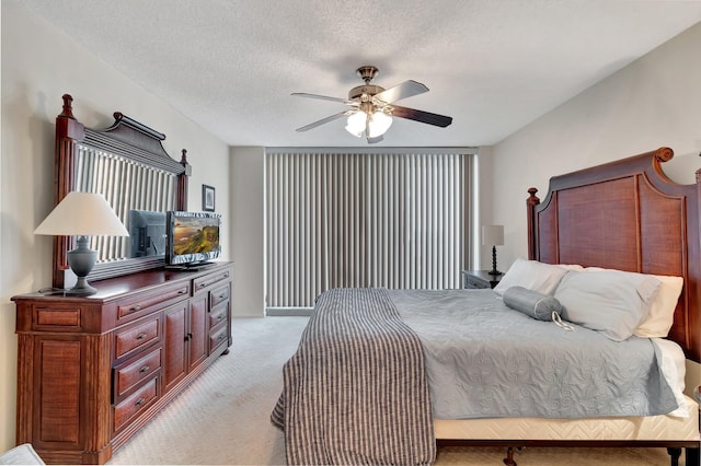 bedroom with ceiling fan, light colored carpet, and a textured ceiling