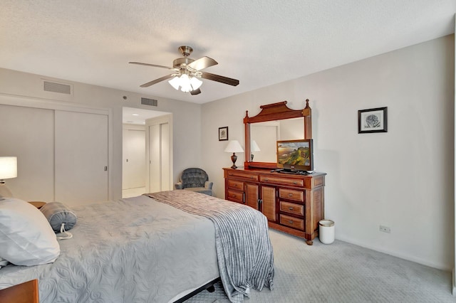 bedroom with ceiling fan, light colored carpet, a closet, and a textured ceiling