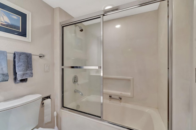 bathroom featuring toilet and combined bath / shower with glass door