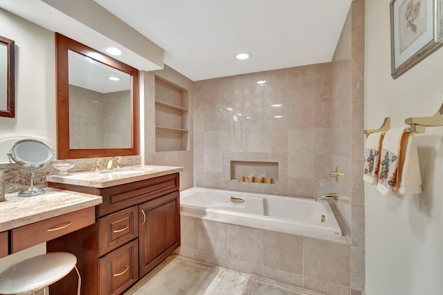 bathroom with vanity, a relaxing tiled tub, and tile walls