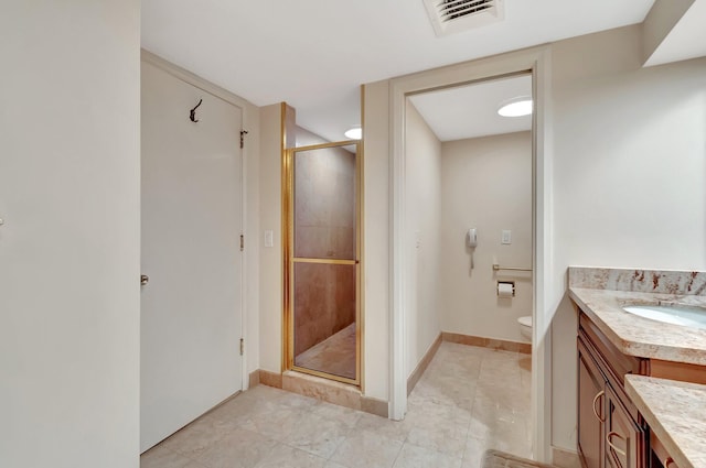 bathroom featuring vanity, toilet, and a shower with door