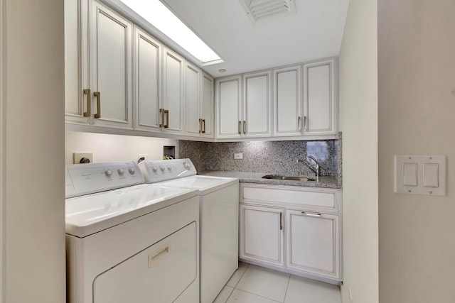 laundry area featuring light tile patterned flooring, cabinets, sink, and washer and dryer