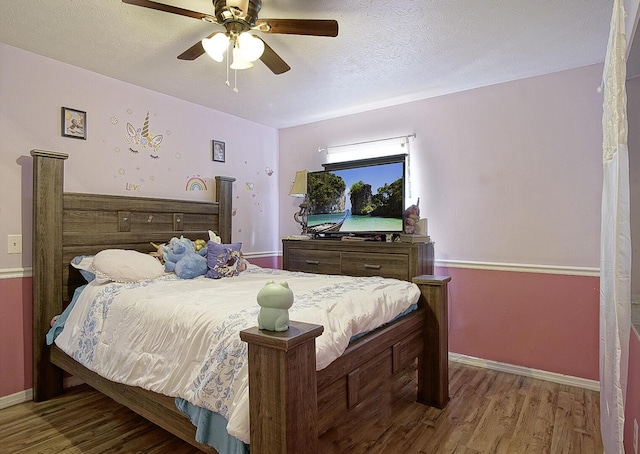 bedroom with ceiling fan, wood-type flooring, and a textured ceiling