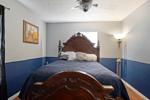 bedroom with ceiling fan, hardwood / wood-style floors, and a textured ceiling