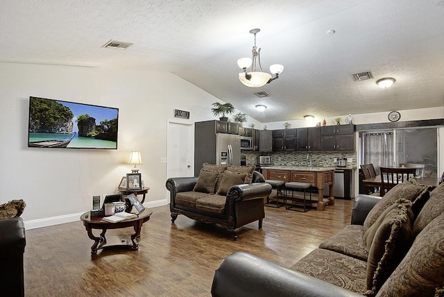 living room with a textured ceiling, dark hardwood / wood-style flooring, and lofted ceiling