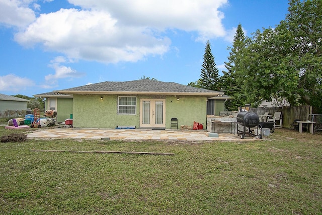 rear view of property featuring french doors, a lawn, and a patio