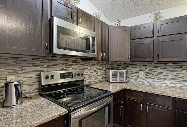 kitchen featuring backsplash, appliances with stainless steel finishes, dark brown cabinets, and a textured ceiling