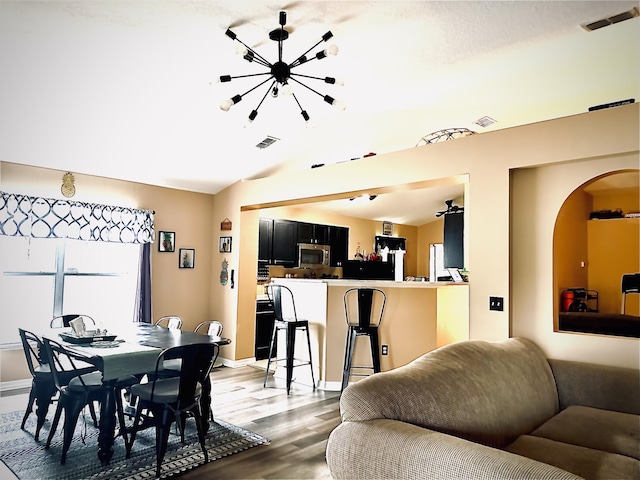 dining room featuring hardwood / wood-style flooring, a chandelier, and vaulted ceiling