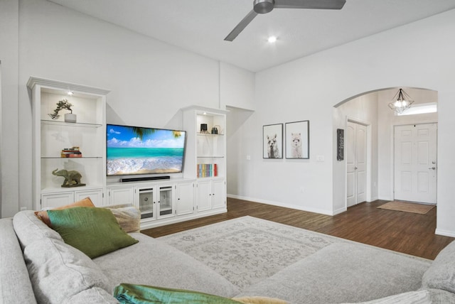 living room featuring arched walkways, wood finished floors, a ceiling fan, built in features, and baseboards