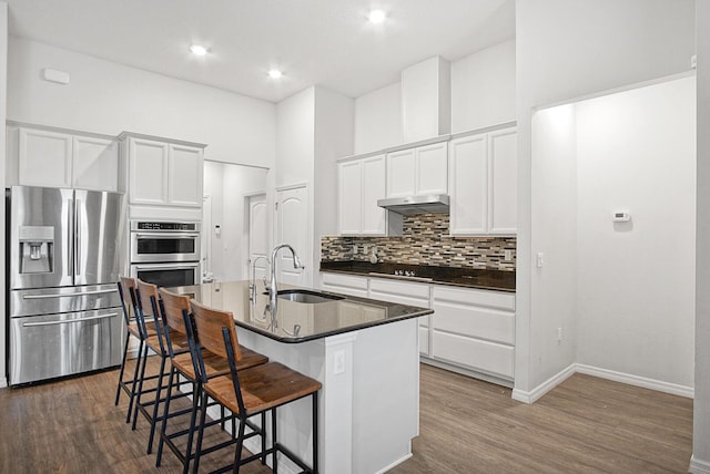 kitchen featuring sink, appliances with stainless steel finishes, a kitchen island with sink, white cabinetry, and a kitchen breakfast bar