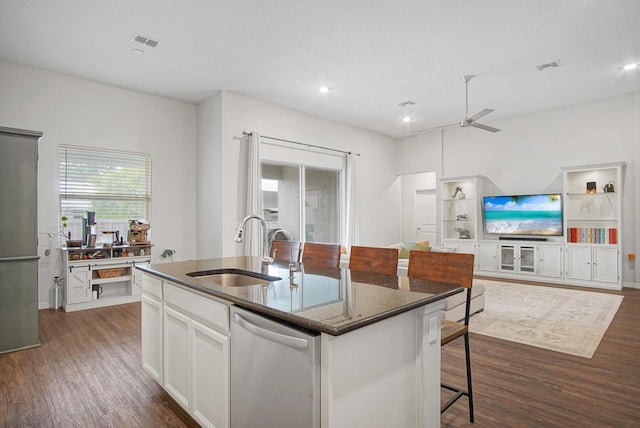 kitchen featuring sink, white cabinetry, dark stone countertops, dishwasher, and an island with sink