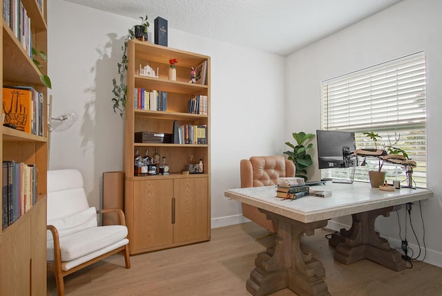 home office with light hardwood / wood-style flooring and a textured ceiling