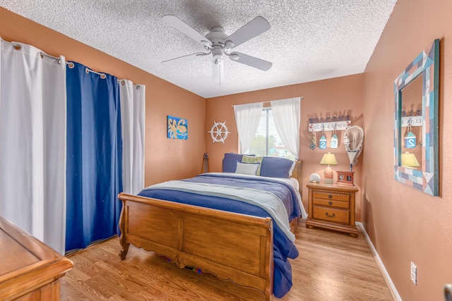 bedroom with ceiling fan, light hardwood / wood-style floors, and a textured ceiling