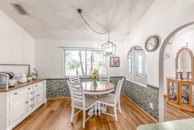 dining room featuring a textured ceiling, light hardwood / wood-style flooring, and a notable chandelier