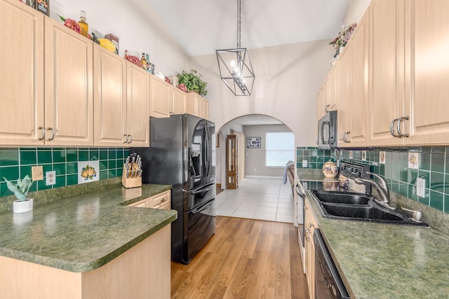 kitchen with black appliances, light hardwood / wood-style floors, hanging light fixtures, sink, and backsplash