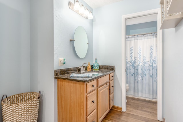 bathroom featuring wood-type flooring, toilet, walk in shower, and vanity