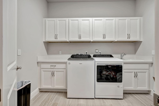 washroom with cabinets, sink, and independent washer and dryer