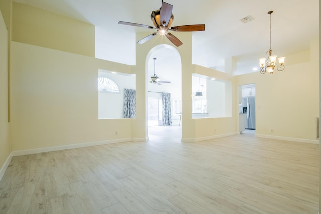 spare room with light wood-style flooring, visible vents, arched walkways, and ceiling fan with notable chandelier