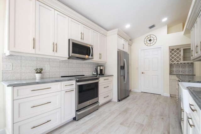 empty room with light hardwood / wood-style flooring, built in shelves, vaulted ceiling, and a healthy amount of sunlight