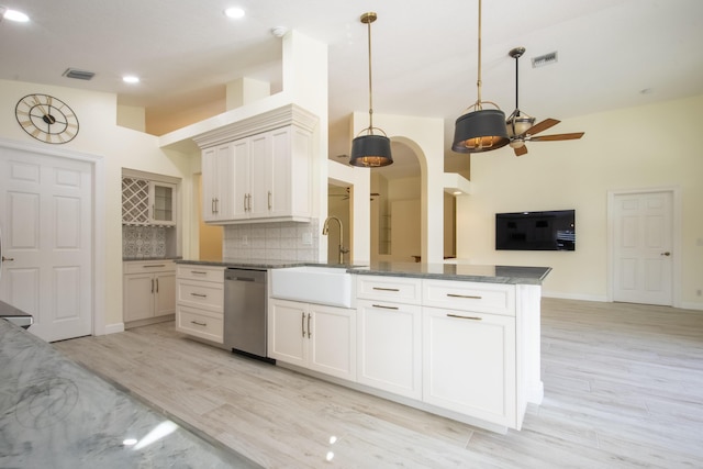 kitchen featuring arched walkways, a sink, visible vents, vaulted ceiling, and stainless steel dishwasher