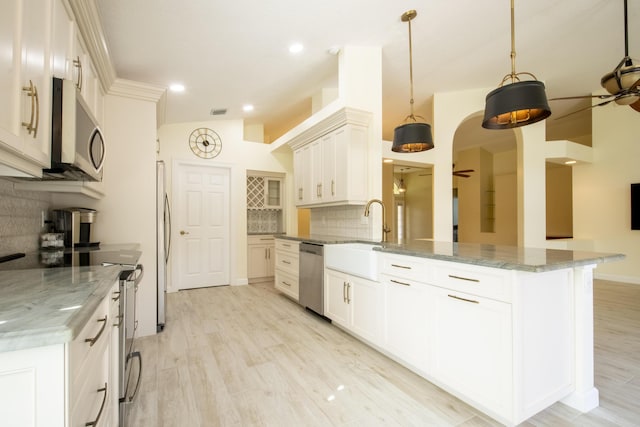 kitchen with tasteful backsplash, hanging light fixtures, white cabinets, and appliances with stainless steel finishes