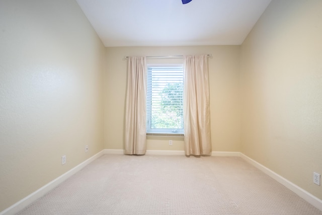 spare room with baseboards and light colored carpet