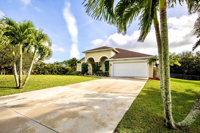 mediterranean / spanish house featuring a garage, concrete driveway, a front yard, and stucco siding