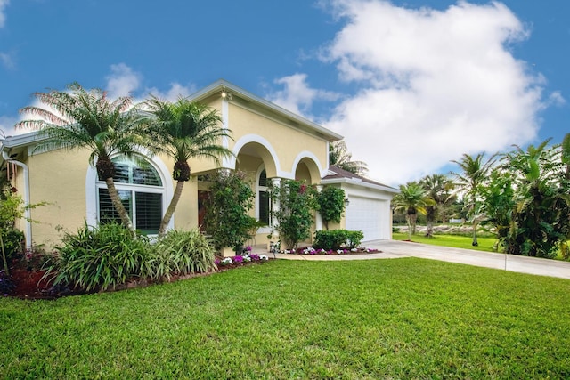 mediterranean / spanish house featuring an attached garage, driveway, a front yard, and stucco siding