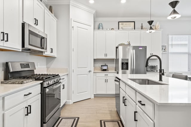 kitchen featuring hanging light fixtures, white cabinetry, appliances with stainless steel finishes, and sink