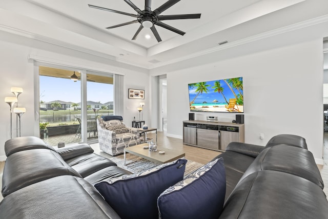 living room with hardwood / wood-style flooring, ceiling fan, crown molding, and a raised ceiling