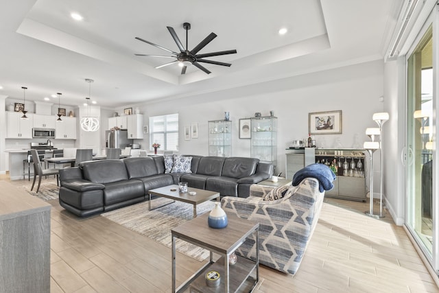 living room featuring crown molding, ceiling fan, and a tray ceiling