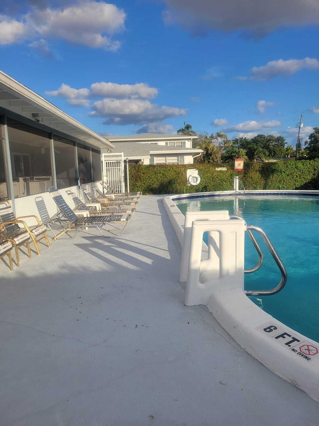 view of pool with a sunroom and a patio