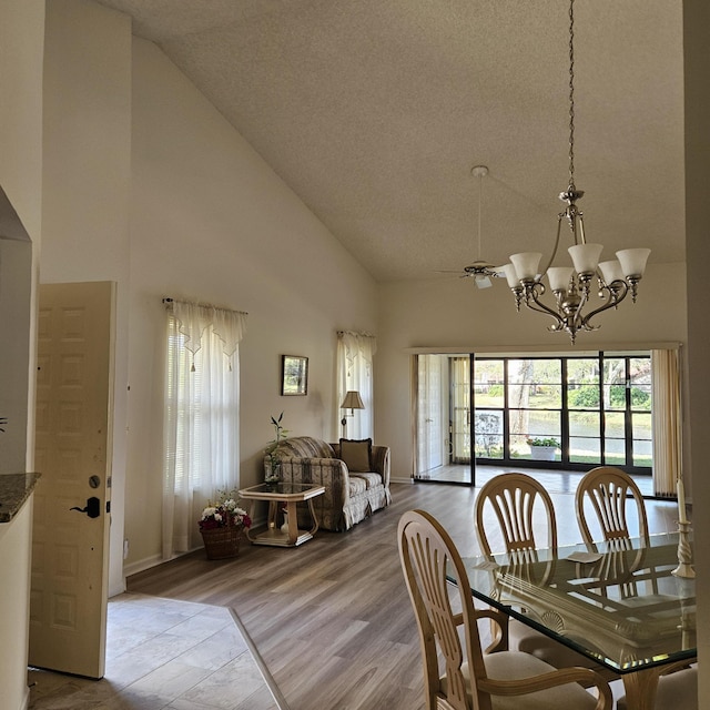 dining area with high vaulted ceiling, an inviting chandelier, and light wood-type flooring