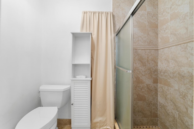 bathroom featuring toilet and a shower with shower door